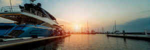 Beautiful view of marina and harbor with yachts and motorboats. Sunset at the ocean. Background