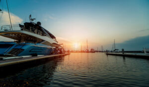 Beautiful view of marina and harbor with yachts and motorboats. Sunset at the ocean. Background
