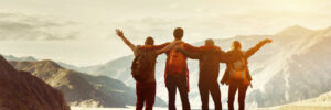 Four happy friends are looking on mountains and having fun together. Space for text. Travel concept