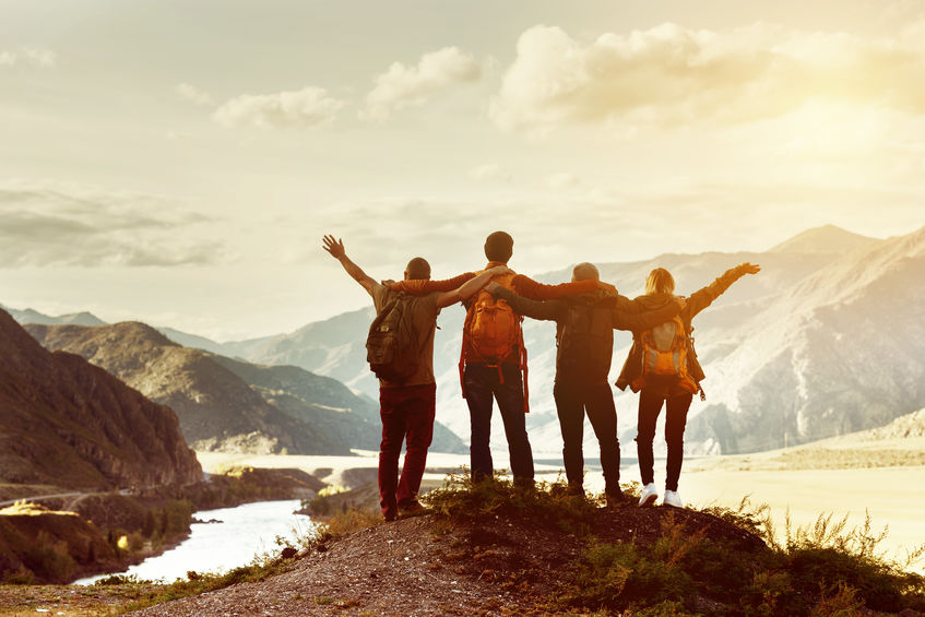 Four happy friends are looking on mountains and having fun together. Space for text. Travel concept
