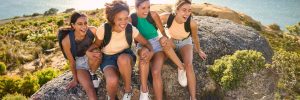 female friends with backpacks on vacation taking a break on hike through countryside